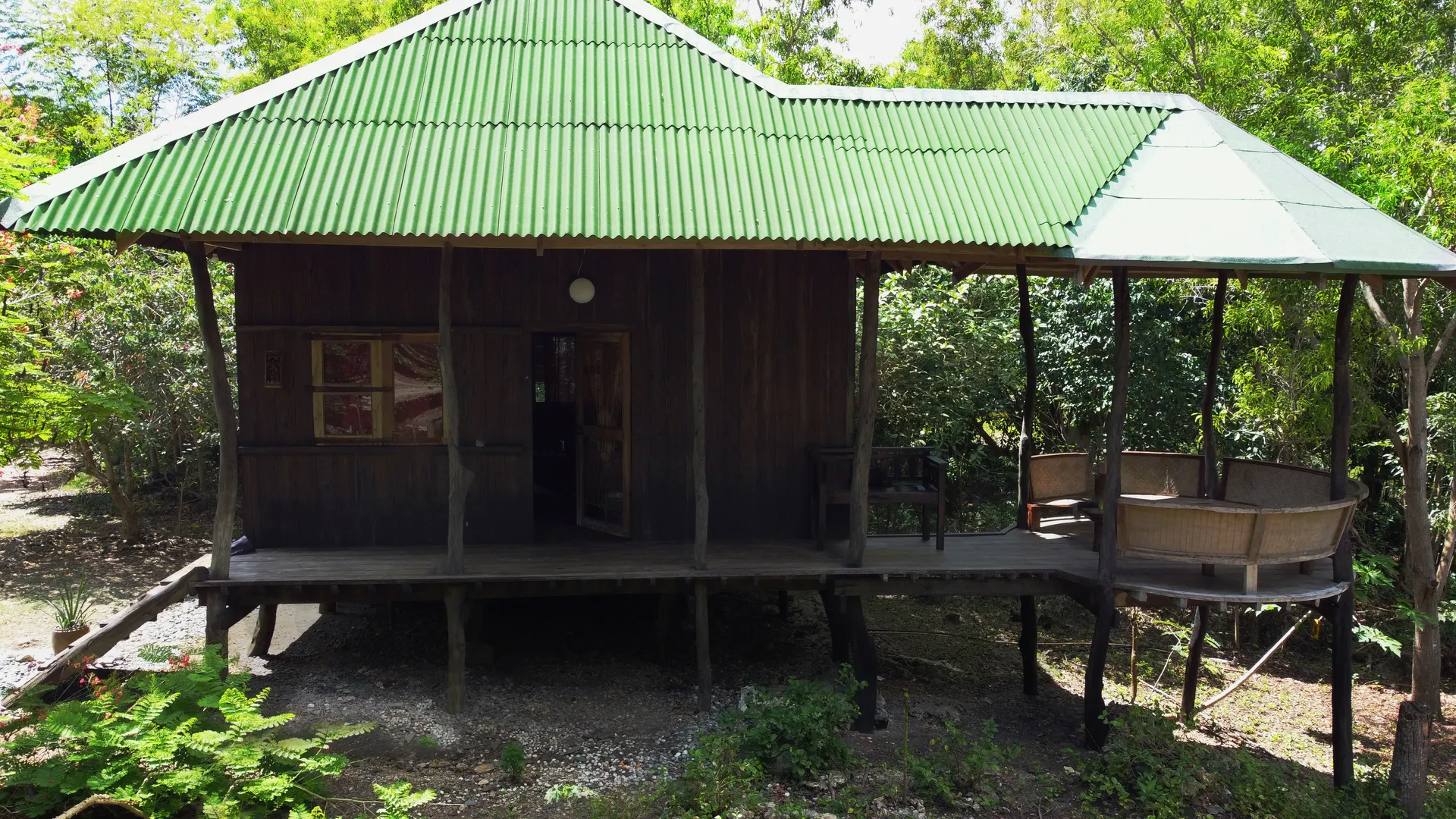 The gate house, a stilted wooden structure with green metal roof on the estate entrance